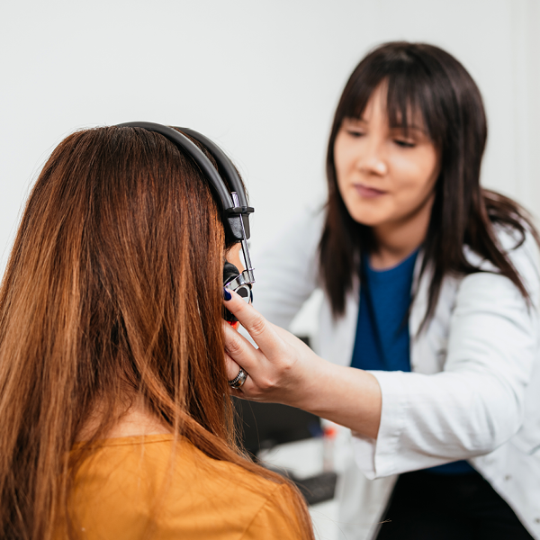 A hearing care professional conducting a professional hearing test using over-ear headphones to assess a patient's hearing ability