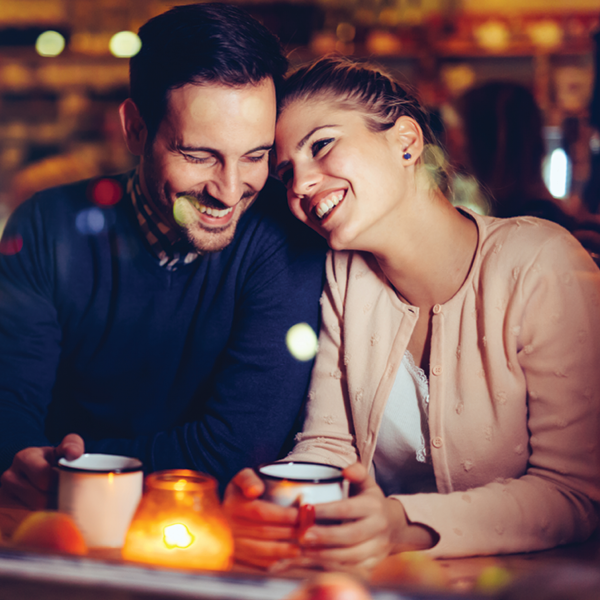Couple laughing together at a cozy cafe, highlighting how clear hearing enhances social connection and joyful moments.