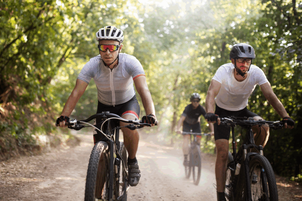 Mountain bikers powering down a wooded trail, illustrating how secure, wind‑smart hearing aids keep pace with high‑movement sports.