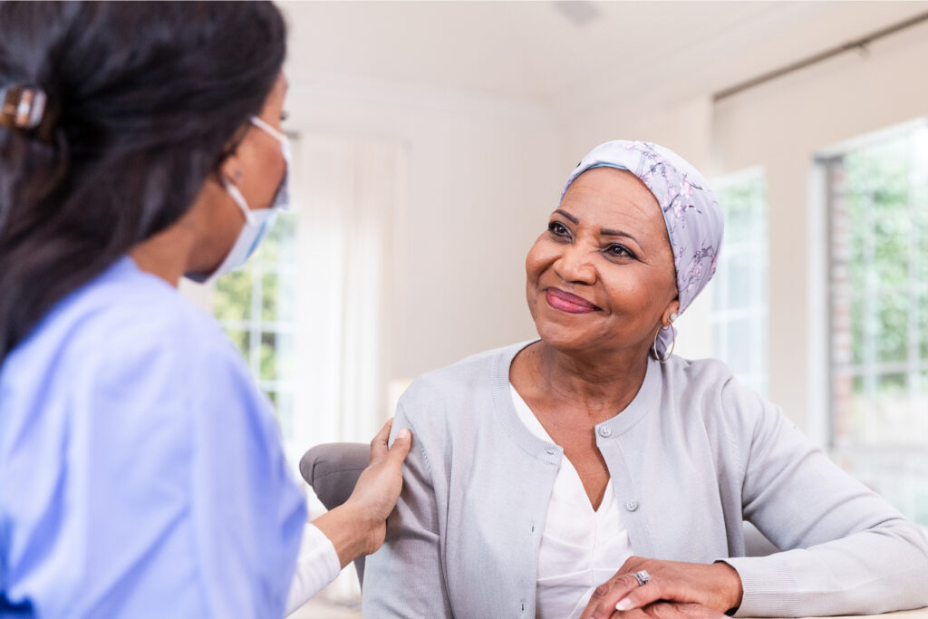 A healthcare provider gently reassures a woman in a headscarf, symbolizing patient support and monitoring during medical treatment that could affect hearing.