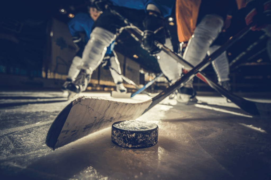 Close-up of a hockey puck on the ice as players in blue and white uniforms face off, capturing the fast-paced excitement and energy of game day.