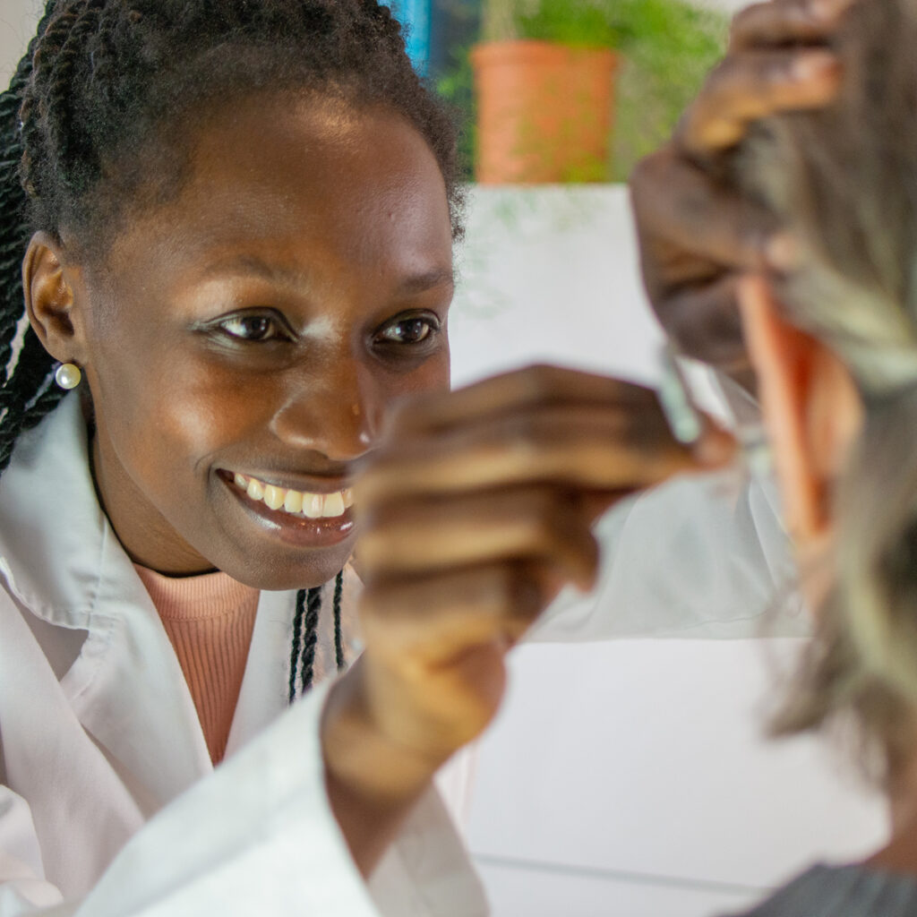 An audiologist smiles while fitting a hearing aid on a patient, demonstrating professional hearing care and personalized attention.
