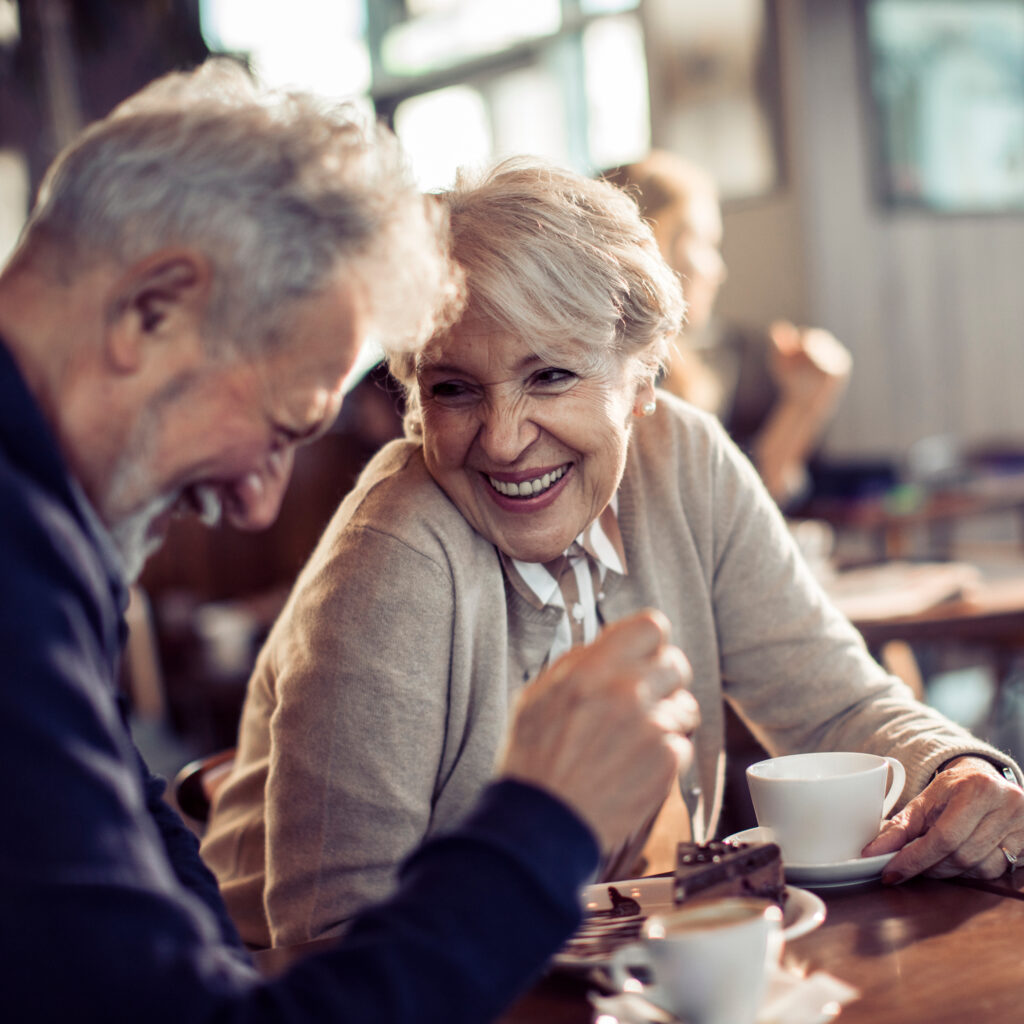 A couple enjoying coffee together at a café, smiling and talking during a relaxed conversation.