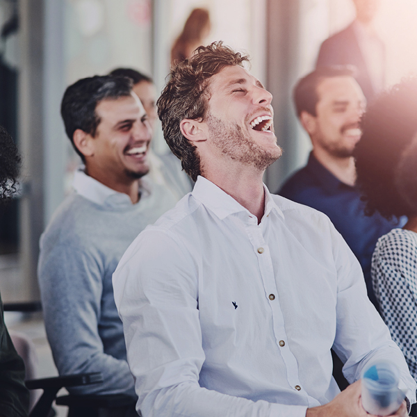 Audience members smiling and laughing while attending a presentation or seminar.