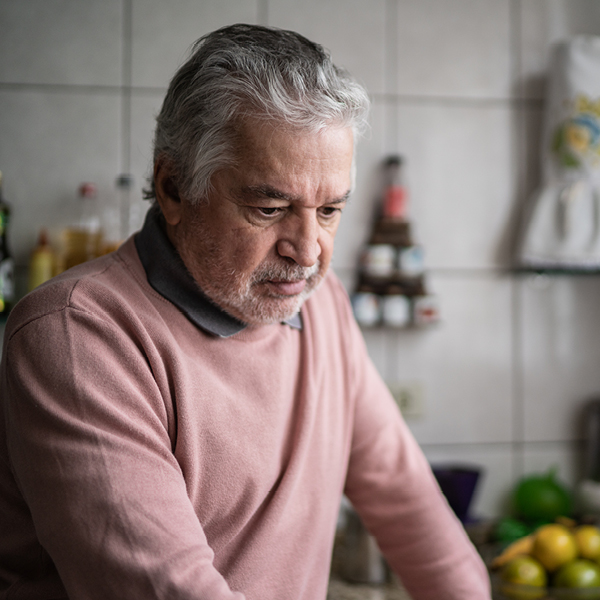 A man standing in his kitchen looking thoughtful, conveying early signs of cognitive strain and the importance of addressing hearing loss.