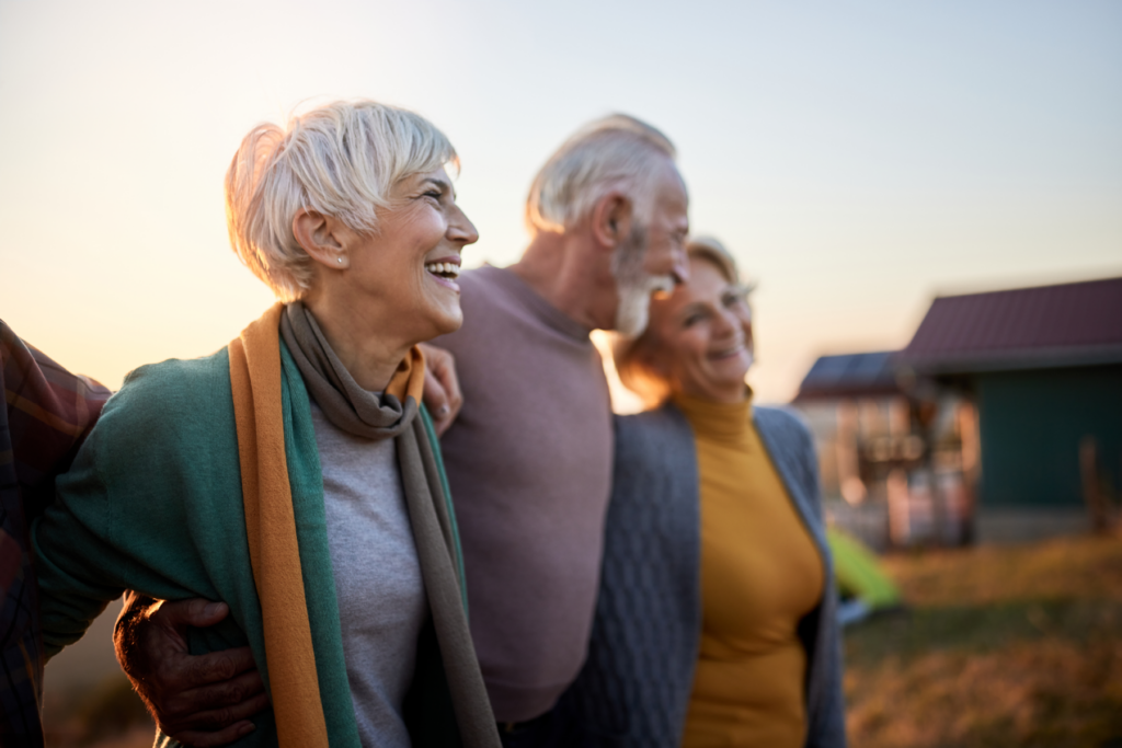 Adults walking together outdoors at sunset, smiling and staying socially connected to support confidence and independence as they age.