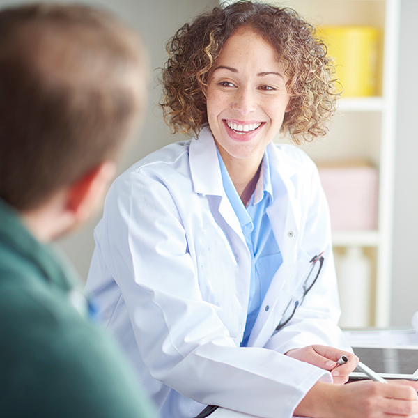 Audiologist smiling and speaking with a patient during a consultation, representing professional tinnitus evaluation and management support.