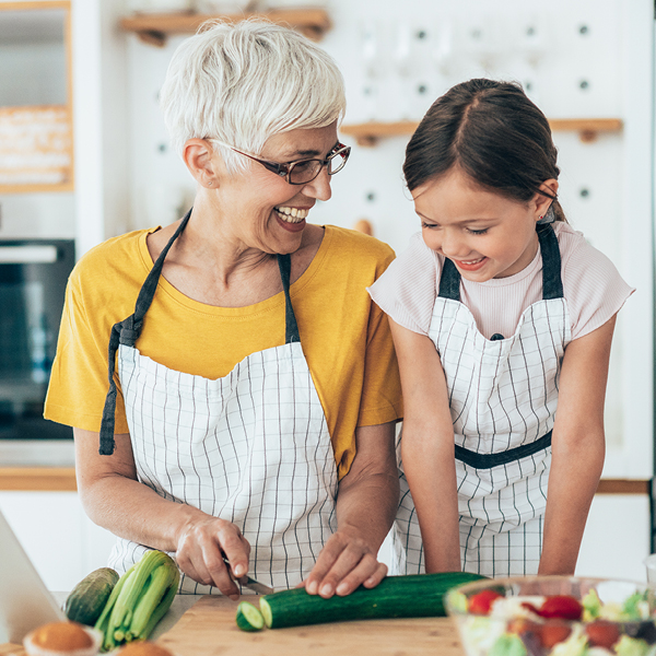 Grandmother and granddaughter cooking together in kitchen, symbolizing meaningful moments reclaimed through tinnitus habituation and improved hearing health.
