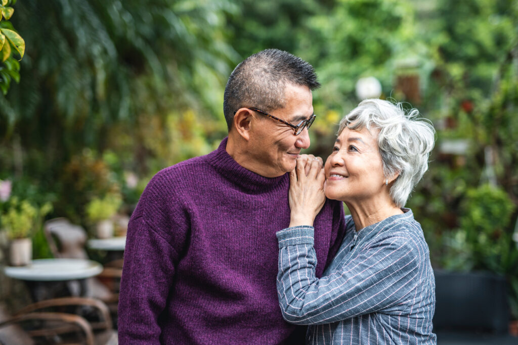 Smiling older couple embracing outdoors enjoying conversation and connection with comfortable hearing support