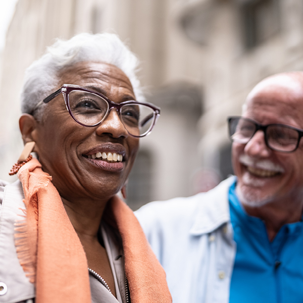 Older adults smiling and talking outdoors, showing how clear hearing and vision support social connection and brain health