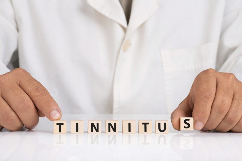 A hearing care professional arranging wooden letter blocks to spell tinnitus, symbolizing professional evaluation and hearing health assessment.
