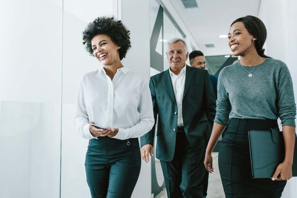 Group of professionals walking through an office hallway, representing everyday communication and social interaction supported by hearing technology