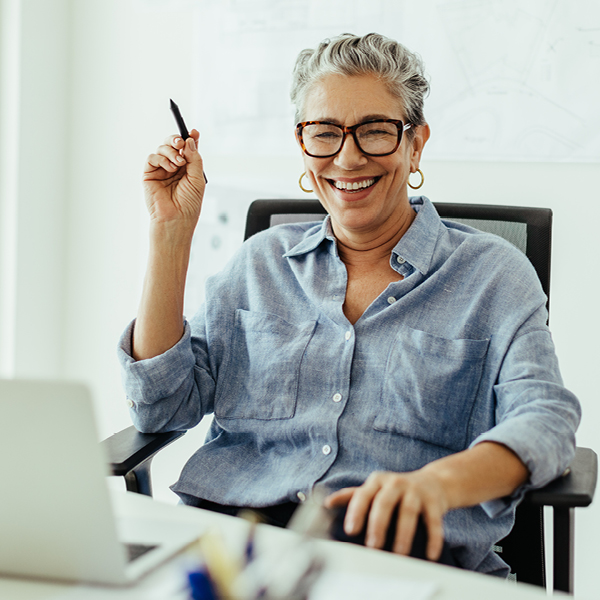 Professional woman smiling while working at a computer, symbolizing confidence after finding tinnitus treatment and sound therapy solutions.
