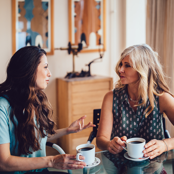 Two women having a face-to-face conversation over coffee, demonstrating effective communication strategies for hearing loss
