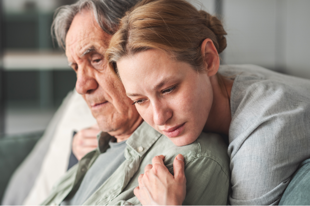A young woman comforting an older man, illustrating the emotional impact of hearing loss on relationships and the importance of supportive communication