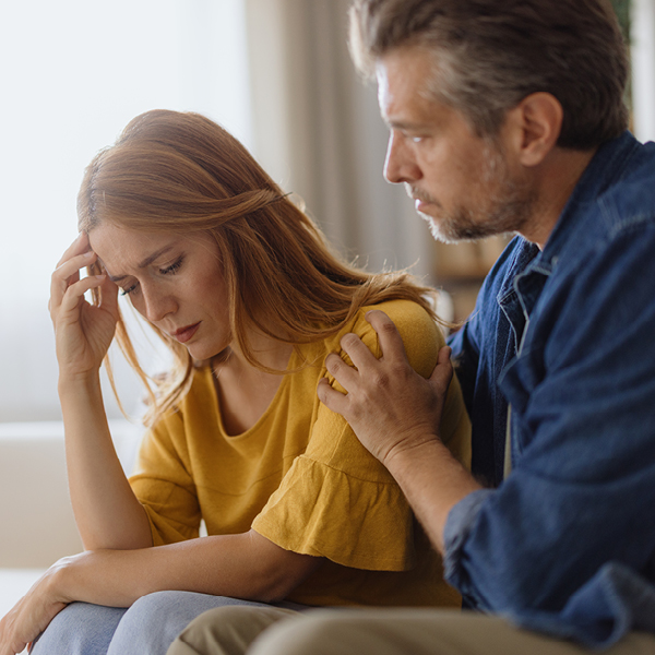 Man comforting a distressed woman, representing the emotional and relationship strain that untreated unilateral hearing loss can cause
