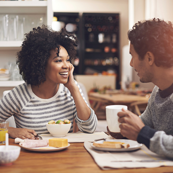 Young couple enjoying easy conversation over breakfast, illustrating improved communication after hearing loss treatment