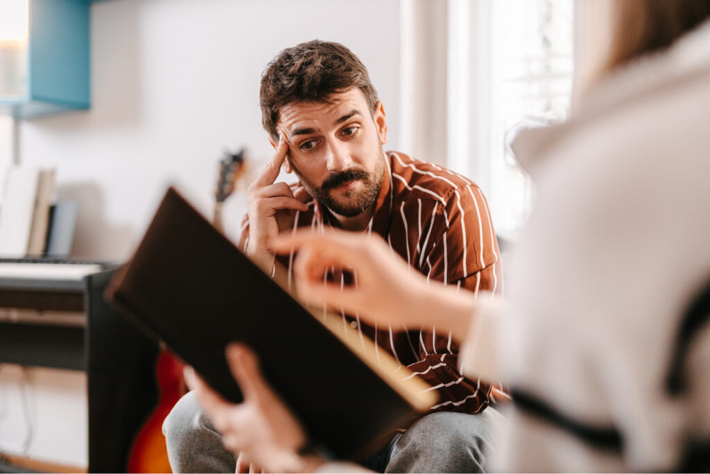 Man with a concerned expression listening intently during a conversation, representing the listening effort associated with unilateral hearing loss