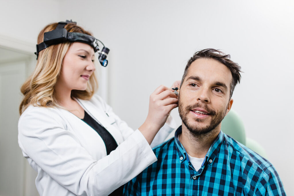 Audiologist checking patient's ear