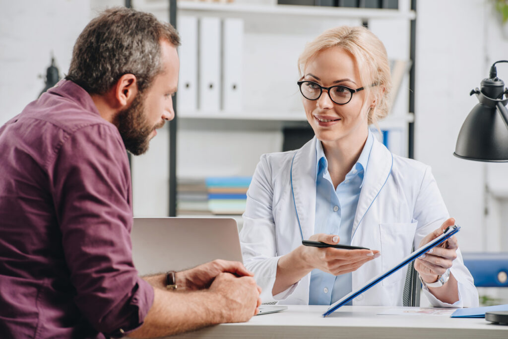 Audiologist in a white lab coat reviewing hearing aid options with a patient during a consultation