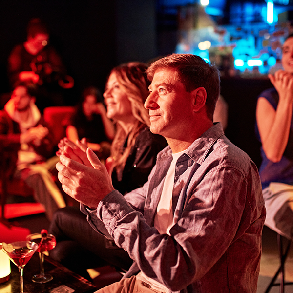 Audience members engaged and applauding at a live performance venue, illustrating the benefit of accessible audio in entertainment settings.