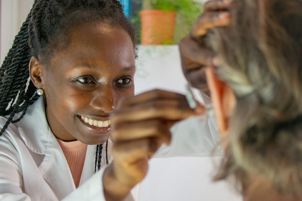 Audiologist smiling while examining a patient's ear during a hearing consultation
