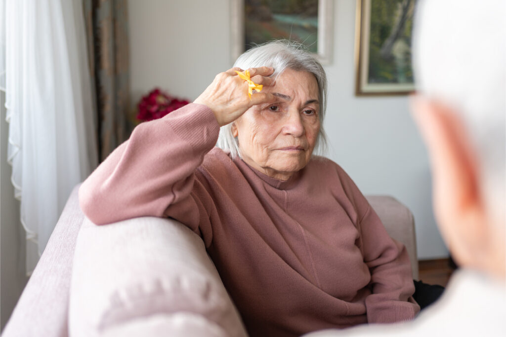 A woman sitting in a living room, struggling to understand someone speaking.