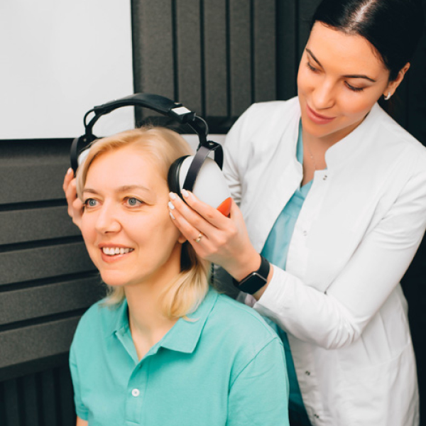 A woman is being fit for a hearing test by an audiologist